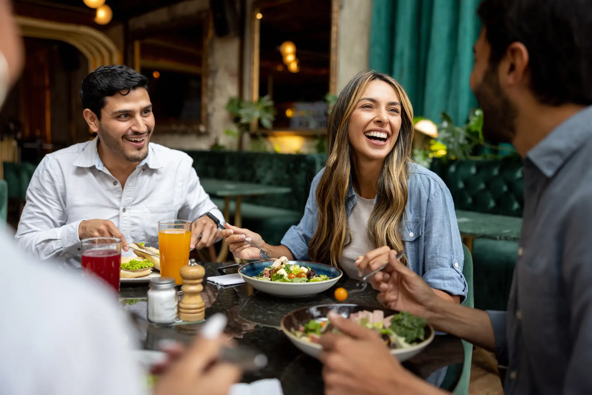 Young adults laughing and enjoying a healthy meal and fresh juice at a restaurant